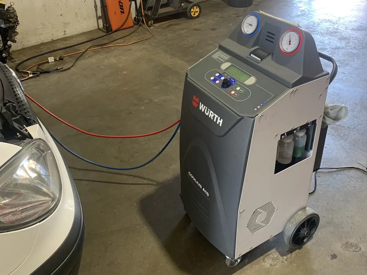 A Wurth air-conditioning service machine with its red and blue hoses laid out on the workshop floor.