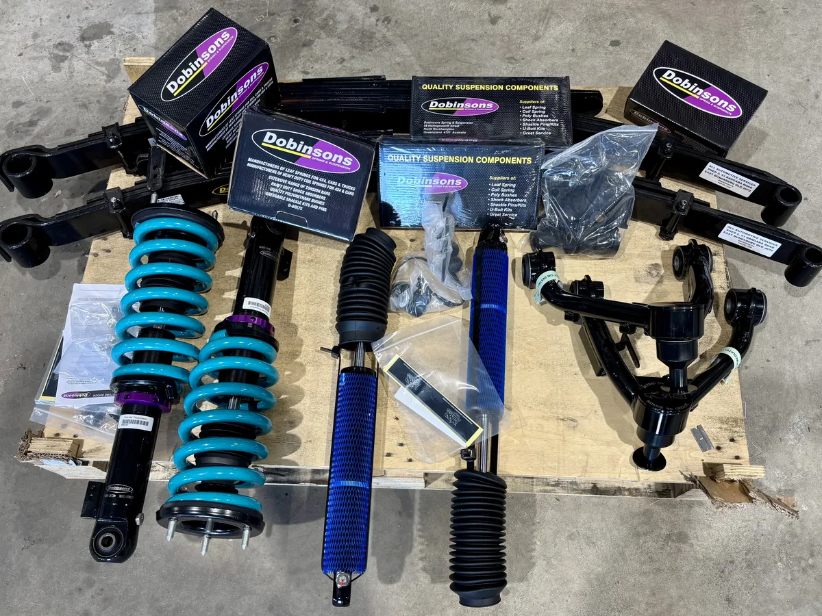 A Dobinsons suspension kit laid out on a pallet with coil-over shocks, springs and control arms.