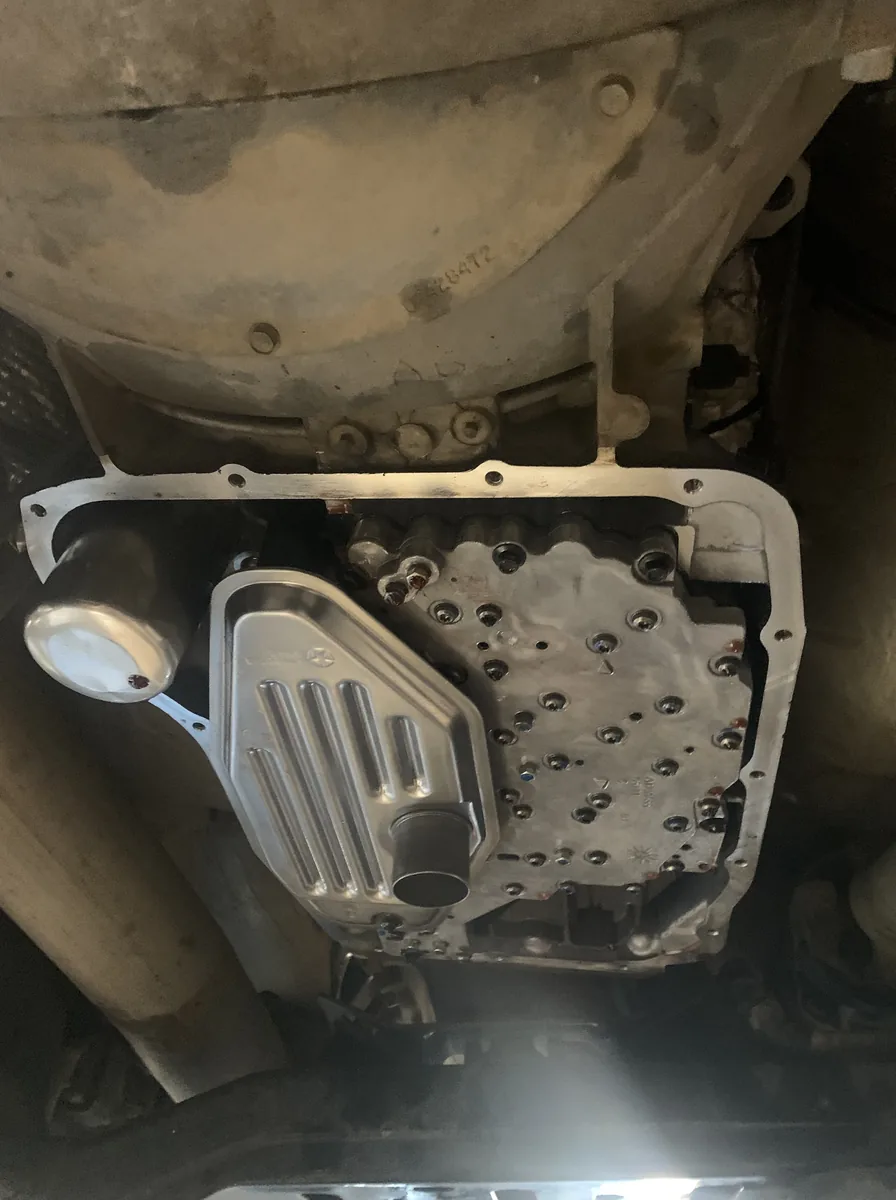 A transmission seen from underneath with its pan removed, showing the filter and valve body.